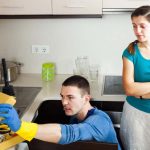 homeowner watches Plumber fixing a leak under the sink